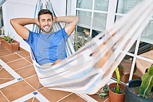 Young hispanic man relaxed smiling happy lying on the hammock at terrace