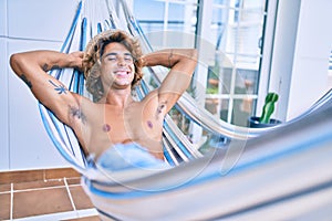 Young hispanic man relaxed smiling happy lying on the hammock at terrace