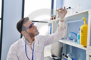 Young hispanic man scientist looking test tube at laboratory