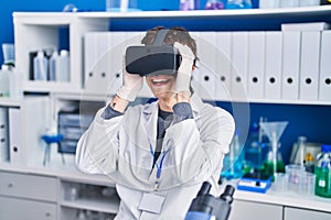 Young hispanic man scientist using virtual reality glasses at laboratory