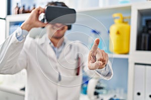 Young hispanic man scientist using virtual reality glasses at laboratory