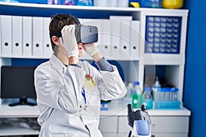 Young hispanic man scientist using virtual reality glasses at laboratory