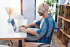 Young hispanic man sitting on wheelchair teleworking at home