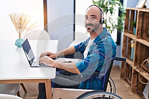 Young hispanic man sitting on wheelchair teleworking at home