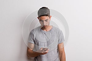 Young hispanic man with smartphone standing in a studio, text messaging.