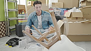 Young hispanic man smiling confident drilling chair at new home