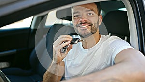 Young hispanic man smiling confident holding key of new car at street