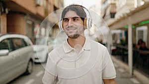 Young hispanic man smiling confident listening to music and dancing at coffee shop terrace