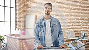 Young hispanic man smiling confident standing by clotheline at laundry room