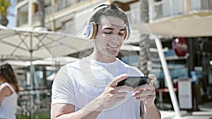 Young hispanic man smiling confident watching video on smartphone at coffee shop terrace