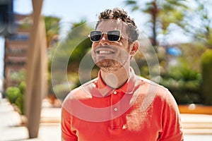 Young hispanic man smiling confident wearing sunglasses at park