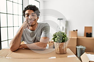 Young hispanic man smiling happy moving at new home