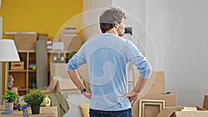 Young hispanic man standing backwards at new home