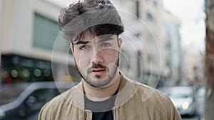 Young hispanic man standing with sadness expression at street