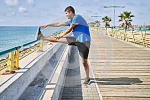 Young hispanic man stretching leg muscles outdoors