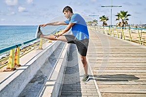 Young hispanic man stretching leg muscles outdoors