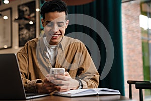 Young hispanic man student sitting at the cafe table indoors