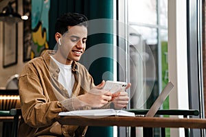 Young hispanic man student sitting at the cafe table indoors