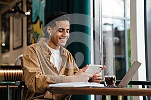 Young hispanic man student sitting at the cafe table indoors