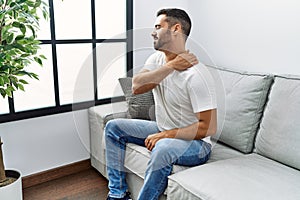 Young hispanic man touching neck suffering for back ache at home