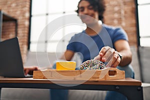 Young hispanic man using laptop having breakfast at home