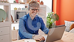 Young hispanic man using laptop and headphones sitting on table at dinning room