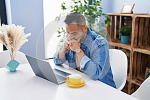 Young hispanic man using laptop with worried expression at home