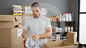 Young hispanic man volunteer packing clothes on cardboard box at charity center