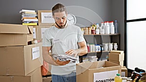 Young hispanic man volunteer packing clothes on cardboard box at charity center