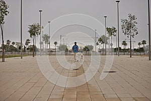 Young Hispanic man, walking his dog on the street alone in the early morning. Concept, dogs, pets, animals, friends