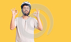 Young hispanic man wearing bike helmet relax and smiling with eyes closed doing meditation gesture with fingers