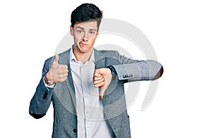 Young hispanic man wearing business clothes doing thumbs up and down, disagreement and agreement expression