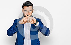 Young hispanic man wearing business jacket rejection expression crossing fingers doing negative sign