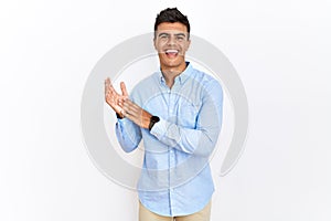 Young hispanic man wearing business shirt standing over isolated background clapping and applauding happy and joyful, smiling