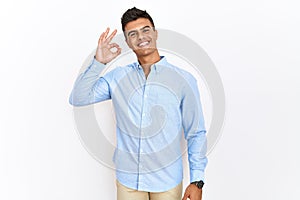 Young hispanic man wearing business shirt standing over isolated background smiling positive doing ok sign with hand and fingers