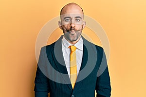 Young hispanic man wearing business suit and tie making fish face with lips, crazy and comical gesture