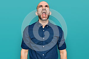 Young hispanic man wearing casual clothes angry and mad screaming frustrated and furious, shouting with anger