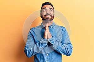 Young hispanic man wearing casual clothes begging and praying with hands together with hope expression on face very emotional and