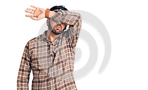 Young hispanic man wearing casual clothes covering eyes with arm, looking serious and sad