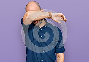 Young hispanic man wearing casual clothes covering eyes with arm, looking serious and sad