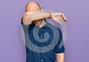 Young hispanic man wearing casual clothes covering eyes with arm, looking serious and sad photo