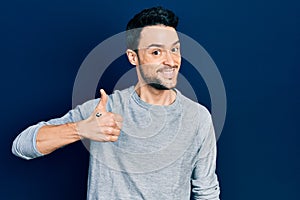 Young hispanic man wearing casual clothes doing happy thumbs up gesture with hand