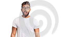 Young hispanic man wearing casual clothes and glasses afraid and shocked with surprise and amazed expression, fear and excited