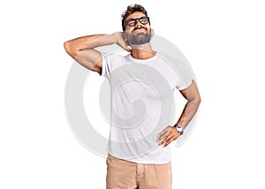 Young hispanic man wearing casual clothes and glasses suffering of neck ache injury, touching neck with hand, muscular pain