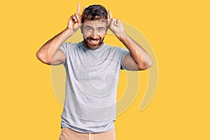 Young hispanic man wearing casual clothes posing funny and crazy with fingers on head as bunny ears, smiling cheerful