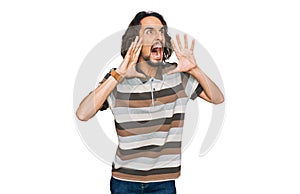 Young hispanic man wearing casual clothes shouting angry out loud with hands over mouth