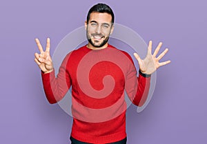 Young hispanic man wearing casual clothes showing and pointing up with fingers number seven while smiling confident and happy