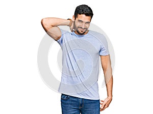 Young hispanic man wearing casual clothes suffering of neck ache injury, touching neck with hand, muscular pain