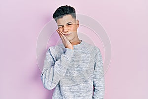Young hispanic man wearing casual clothes touching mouth with hand with painful expression because of toothache or dental illness