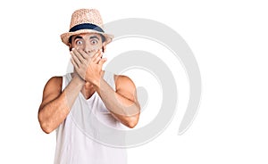 Young hispanic man wearing casual summer hat shocked covering mouth with hands for mistake